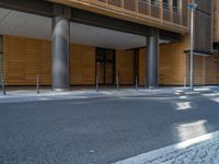 a road through which is a large modern building with an awning over it's entrance