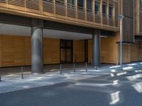 a road through which is a large modern building with an awning over it's entrance