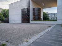 a red fire hydrant sitting next to a concrete building under an overhange