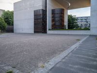 a red fire hydrant sitting next to a concrete building under an overhange