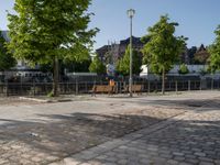 an empty park on the corner of a street next to a fence and benches in a city