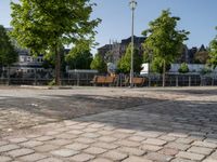 an empty park on the corner of a street next to a fence and benches in a city