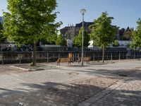 an empty park on the corner of a street next to a fence and benches in a city