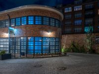 some dark blue windows in an industrial building with no one on the street to the right