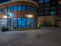 some dark blue windows in an industrial building with no one on the street to the right