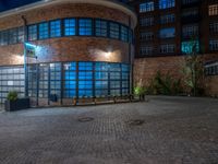 some dark blue windows in an industrial building with no one on the street to the right