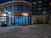 some dark blue windows in an industrial building with no one on the street to the right