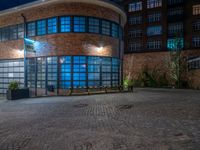 some dark blue windows in an industrial building with no one on the street to the right