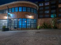 some dark blue windows in an industrial building with no one on the street to the right