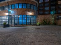 some dark blue windows in an industrial building with no one on the street to the right