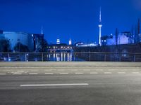 an empty road, with the sky in the background with a city view and a building and fence