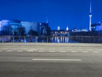 an empty road, with the sky in the background with a city view and a building and fence