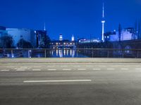 an empty road, with the sky in the background with a city view and a building and fence