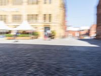 blurred picture of a person riding a bike near buildings in an old town square,