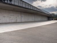 the skate boarder is balancing his board against a wall in an empty concrete space