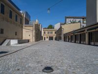 the sidewalk is paved with stones and has a bench in front of it, with no people inside