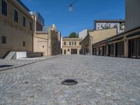 the sidewalk is paved with stones and has a bench in front of it, with no people inside