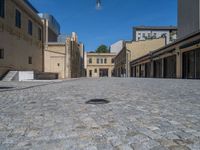 the sidewalk is paved with stones and has a bench in front of it, with no people inside