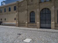 the sidewalk is paved with stones and has a bench in front of it, with no people inside