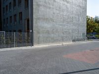 a woman rides on her skateboard along the sidewalk near a building that is concrete and holds the board