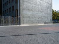 a woman rides on her skateboard along the sidewalk near a building that is concrete and holds the board