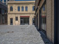 the sidewalk is paved with stones and has a bench in front of it, with no people inside