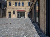 the sidewalk is paved with stones and has a bench in front of it, with no people inside