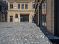 the sidewalk is paved with stones and has a bench in front of it, with no people inside