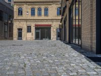 the sidewalk is paved with stones and has a bench in front of it, with no people inside