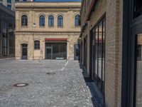 the sidewalk is paved with stones and has a bench in front of it, with no people inside