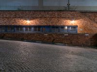 some dark blue windows in an industrial building with no one on the street to the right