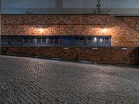 some dark blue windows in an industrial building with no one on the street to the right