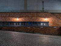 some dark blue windows in an industrial building with no one on the street to the right