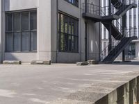 an outdoor stair next to a building next to a sidewalk and a fire escape door