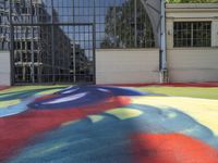 a person sitting down on a colorful floor next to an air ball field in front of a building