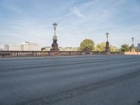 empty asphalt road with street lamp post on bridge and city in background at daytime or night