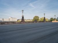 empty asphalt road with street lamp post on bridge and city in background at daytime or night