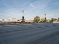 empty asphalt road with street lamp post on bridge and city in background at daytime or night