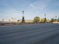 empty asphalt road with street lamp post on bridge and city in background at daytime or night