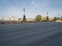 empty asphalt road with street lamp post on bridge and city in background at daytime or night