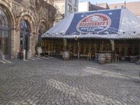 the old time store is selling various items for sale under an awning on cobblestone