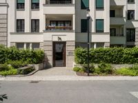 a view of the outside of a building with green shutters and landscaping on the side