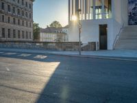 empty street lined with cement buildings next to a tall building with a staircase up to it