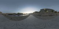 a fish eye photo of a bridge in the city by water and buildings at sunset