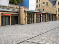 a paved street that has windows in it and a few buildings on it with a red sign