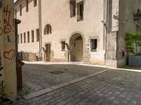 a stone road next to two tall brick buildings with doors and windows on them, one in the middle of a brick patio