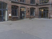 there is an empty sidewalk and brick wall behind the store doors that is the main entrance to a building