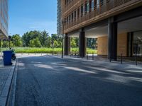 a road through which is a large modern building with an awning over it's entrance