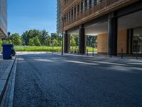 a road through which is a large modern building with an awning over it's entrance