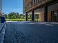 a road through which is a large modern building with an awning over it's entrance